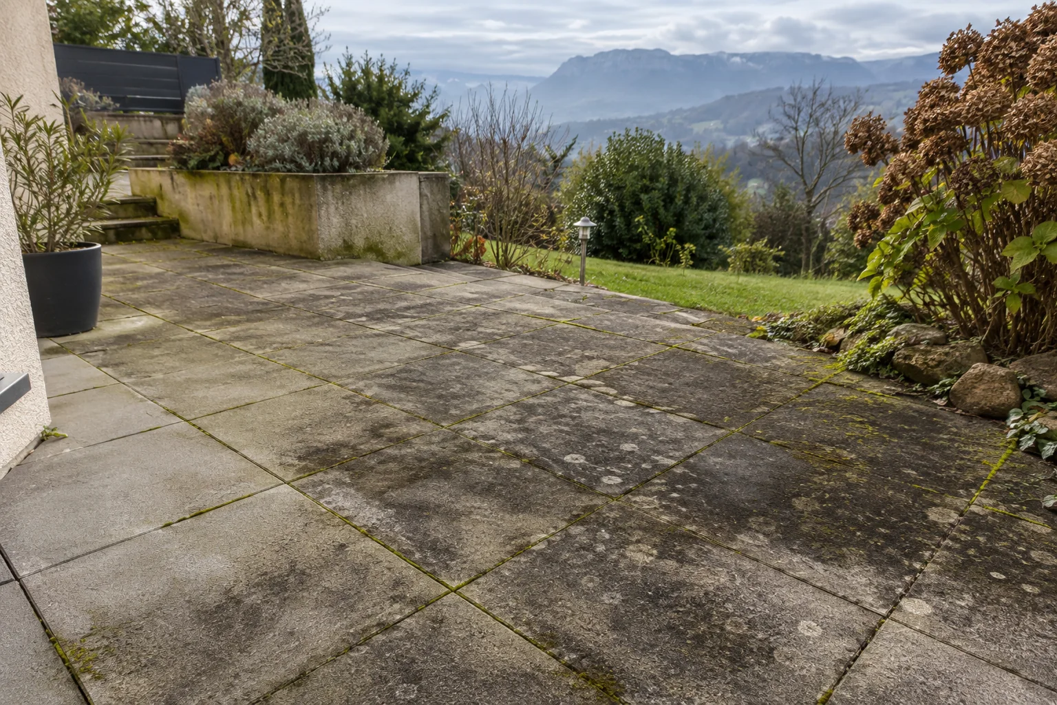 Terrasse en dalles béton et carrelage extérieur avant nettoyage, avec traces noires et mousses